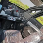 Interior view of a compact vehicle's cabin, showcasing the driver's seat and dashboard controls, covered in protective plastic.