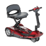 A compact, red, four-wheeled mobility scooter with a cushioned seat, adjustable armrests, and a tiller featuring simple control buttons. The scooter has a footrest and is designed for easy maneuverability, suitable for indoor and outdoor use.