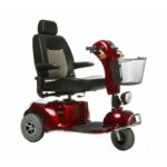 A red mobility scooter with three wheels. It features a comfortable black cushioned seat with a tall backrest and armrests. The scooter has handlebars with controls, a headlight, and a metal basket attached to the front. The wheels are sturdy and suitable for various terrains.