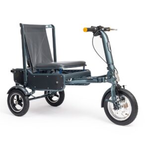 The image shows the eFOLDi Explorer Mobility Scooter, which has a sturdy, dark-colored frame. It features a large, cushioned seat with a black backrest made of a flexible material that likely offers comfortable support. The scooter is equipped with three wheels: two smaller ones at the back and a larger, spoked front wheel, all of which contribute to its stability and maneuverability. The handlebar is equipped with handgrips and controls, and there is a noticeable yellow reflector or light on the side, enhancing visibility for safety. The design suggests that this model provides a balance of comfort and practicality for outdoor use.
