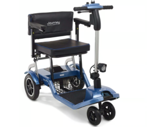 A blue Journey Health & Lifestyle So Lite mobility scooter with a black seat, silver handlebar with a headlight, a black front basket, and four black wheels.