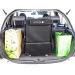An eFOLDi Lite scooter folded and placed in the trunk of a car, demonstrating the scooter's portability and space efficiency.