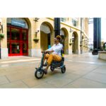 Cheerful person riding the eFOLDi Explorer through a city plaza, illustrating the scooter's functionality and smooth handling in pedestrian areas.