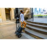 Individual effortlessly transporting the eFOLDi Explorer scooter in its folded state up steps, showcasing its portability and lightweight design for overcoming common urban obstacles.