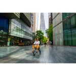 A person enjoying a ride on the eFOLDi Explorer mobility scooter in a modern city area, illustrating the scooter's integration into daily life and its suitability for various urban settings.