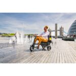 The eFOLDi Explorer scooter in use on a sunny day near a city fountain, showcasing the scooter providing mobility and independence in lively urban environments.