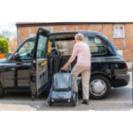 A senior individual loading the eFOLDi Explorer scooter into a taxi, showcasing the scooter's practicality and ease of lifting for travel.