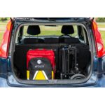 The eFOLDi Lite scooter neatly folded and placed in the boot of a car, alongside a red suitcase, demonstrating the scooter's compactness and ease of transport for active lifestyles.