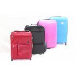 A red fabric suitcase, a black eFOLDi Lite scooter, and colorful hard-shell suitcases side by side, showing the scooter's compact and foldable design, comparable to luggage size for travel readiness.