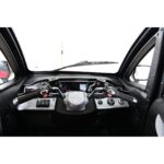 The image features a detailed view of a Green Transporter Q Express vehicle's dashboard, showing dual steering grips, control buttons, and a central display unit.