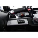 Close-up of the driver's side dashboard controls in a Green Transporter Q Express, featuring a throttle grip, mirror, and various function buttons.