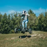 Action shot of a rider jumping the MIA Four X2 scooter off the ground in an off road setting