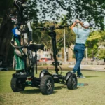 Outdoor view of the MIA Four X2 scooter on a golf course with a golfer swinging in the background