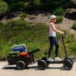Woman riding CycleBoard X-Quad 3000 electric scooter towing a cargo trailer outdoors